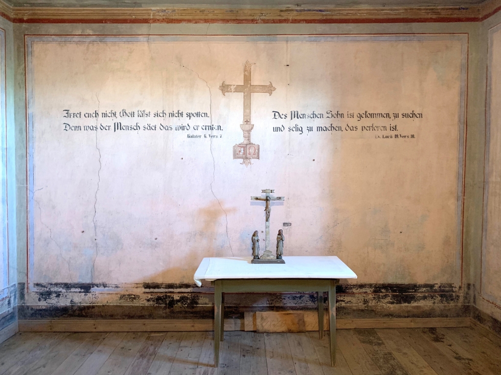 Wanddekoration der Gefängniskapelle mit Bibelsprüchen und Kreuz