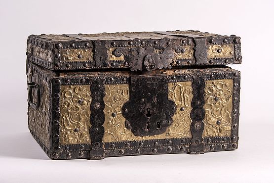 Der Koffer wurde aufwendig mit floral gestaltetem Messingblech überzogen. Das Stück lässt sich zeitlich zwischen 1750 und 1800 einordnen.