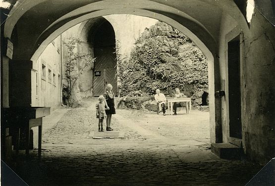 Innenhof von Schloss Weesenstein mit zwei sitzenden Wachleuten und zwei Mädchen im Sommer 1944
