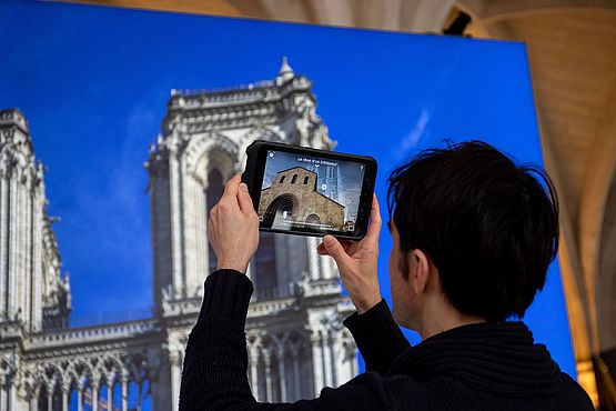 Mit einem Tablet erschließt sich ein Besucher ganz neue Perspektiven auf Notre Dame