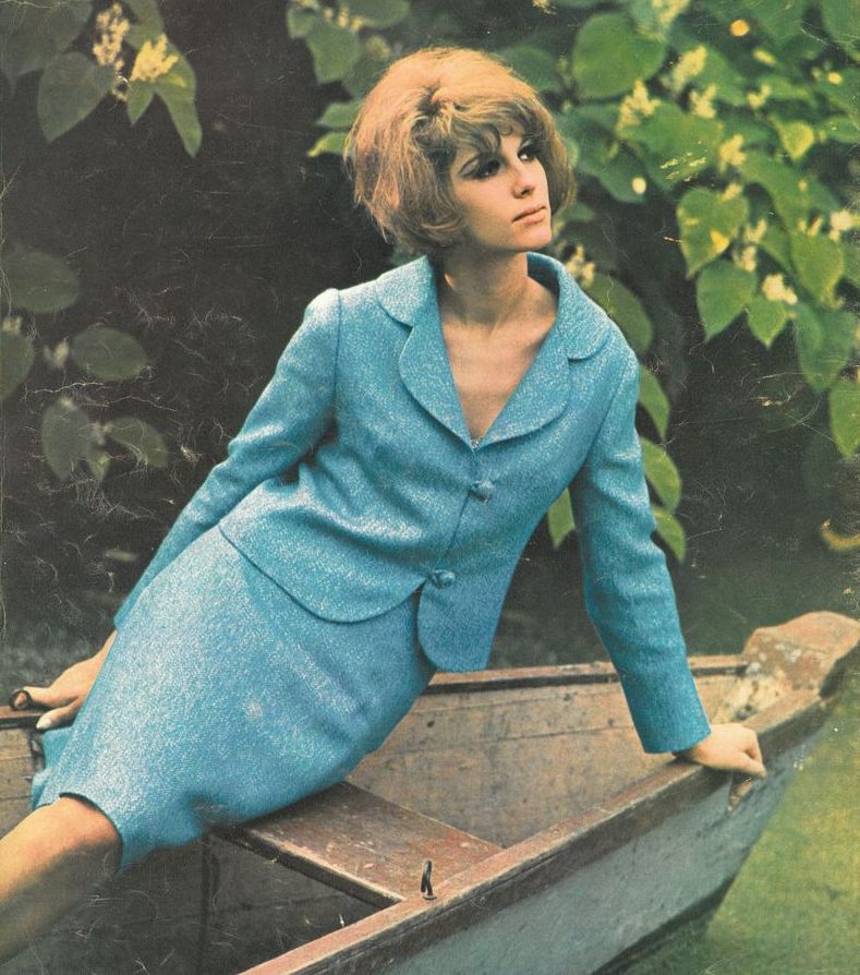 Eine junge Frau in blauem Kostüm posiert während eines Fotoshootings 1966 auf einem kleinen Boot.
