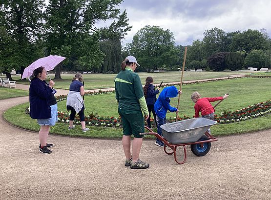Eine Gruppe von Kindern hilft bei der Beet- und Wegepflege im Großen Garten