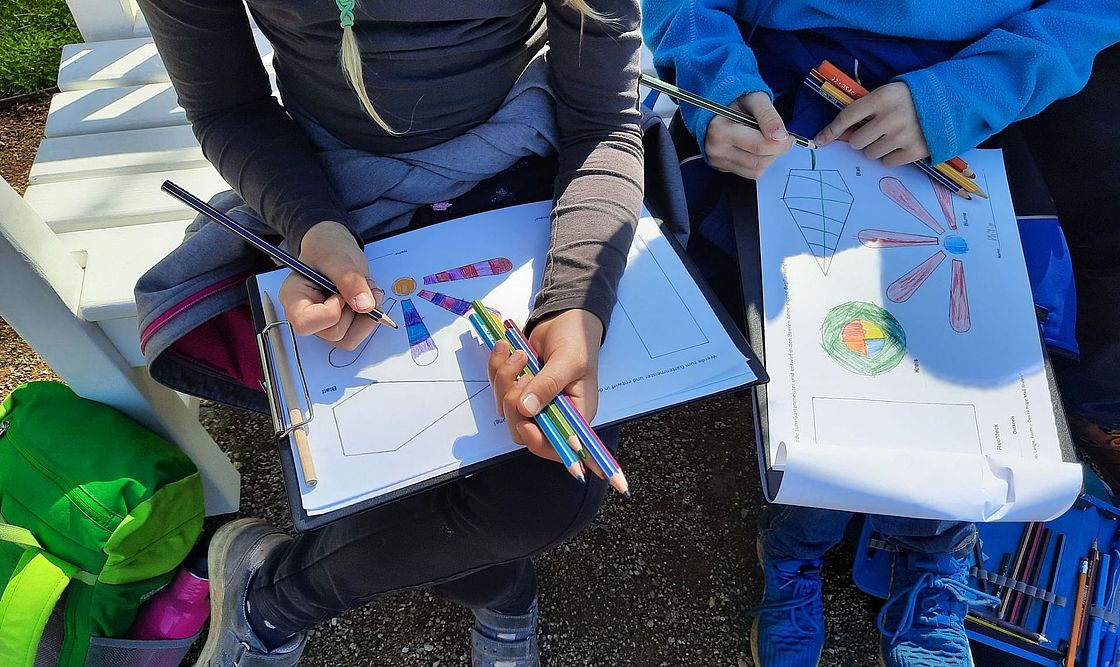 Ein Blick von oben auf die theoretische Gartenplanung von Kindern mit Stiften auf Papier